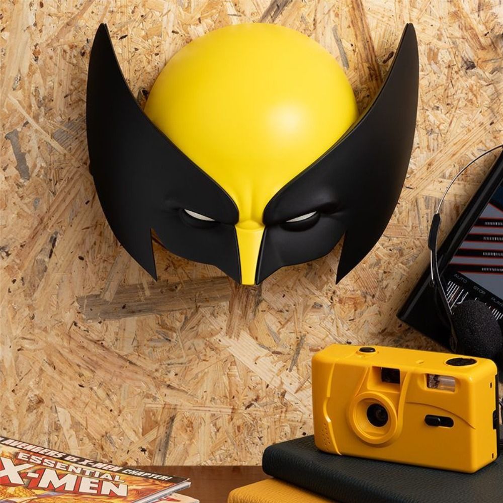 Yellow and black mask on a wooden surface with a yellow camera and X-Men comic book.
