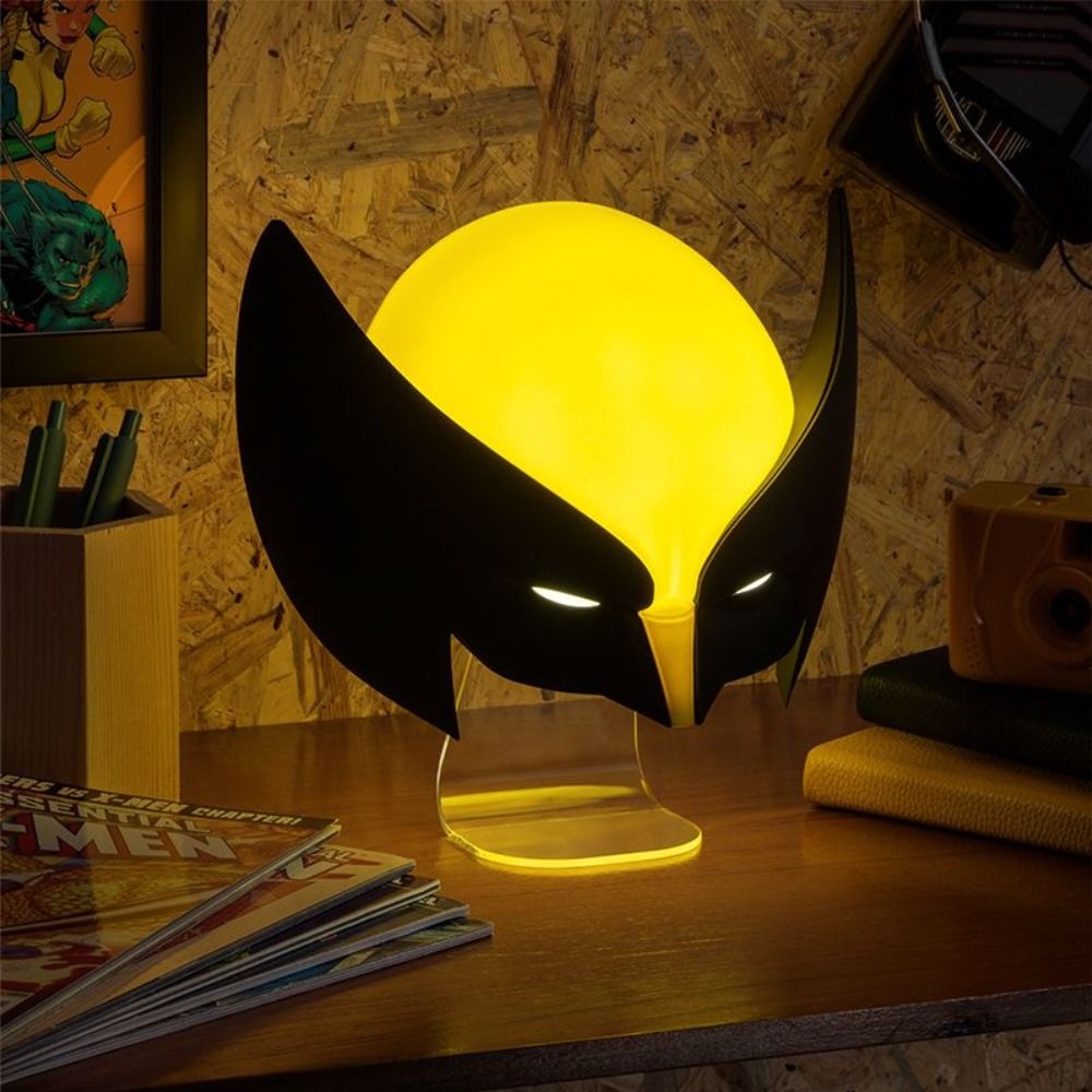 Yellow light bulb-shaped lamp with black wings on a wooden surface.